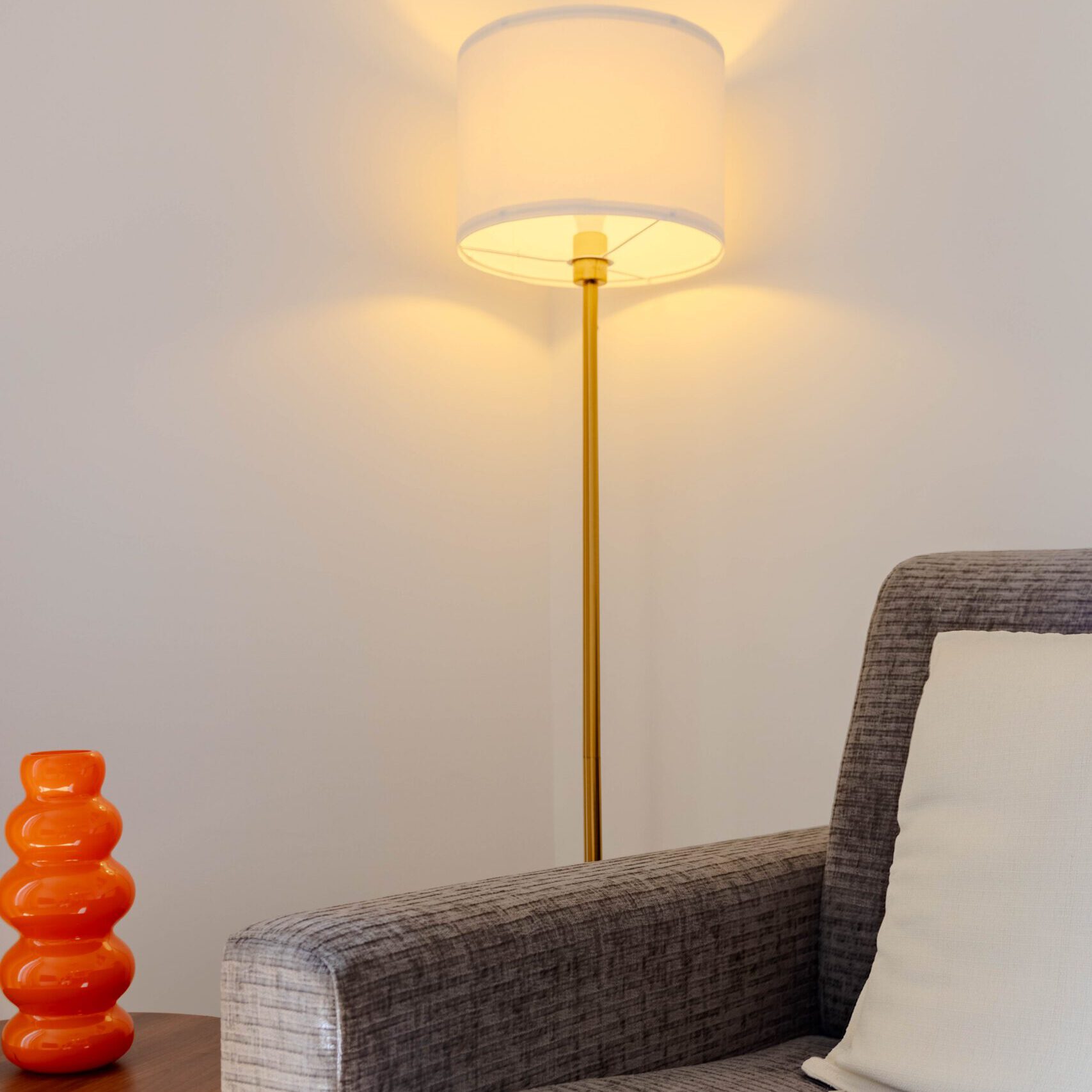 Coin lecture cosy avec grand fauteuil et lampe sur pied pour se poser avec un livre ou un verre.