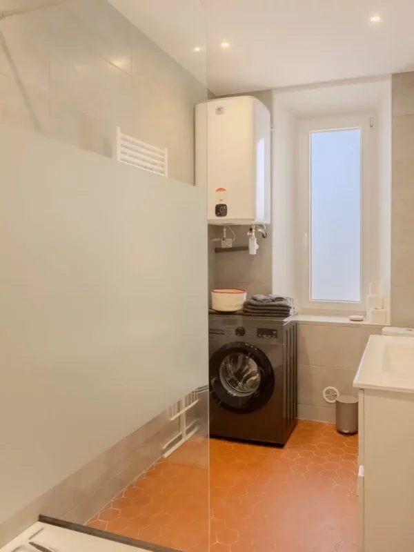 Salle de bain avec espace buanderie pratique avec lave‑linge et rangements, pour des séjours plus longs en toute autonomie.