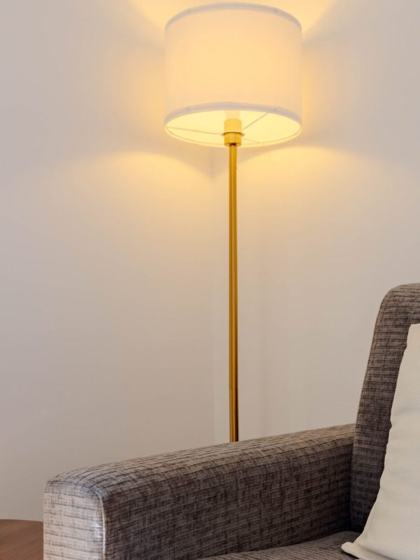 Coin lecture cosy avec grand fauteuil et lampe sur pied pour se poser avec un livre ou un verre.